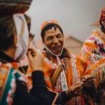 A man in vibrant traditional clothing shares a joyful moment outdoors.